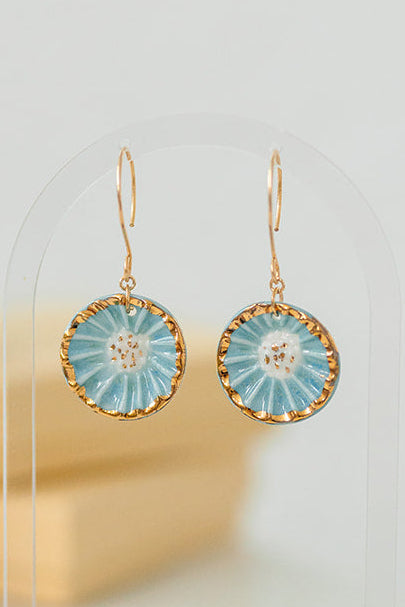 Handcrafted porcelain Anemone earrings with a blue glaze, sculptural radial texture, and hand-applied 22k gold accents.