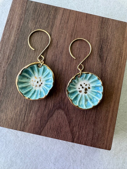 Handcrafted porcelain Anemone earrings with a blue glaze, sculptural radial texture, and hand-applied 22k gold accents.