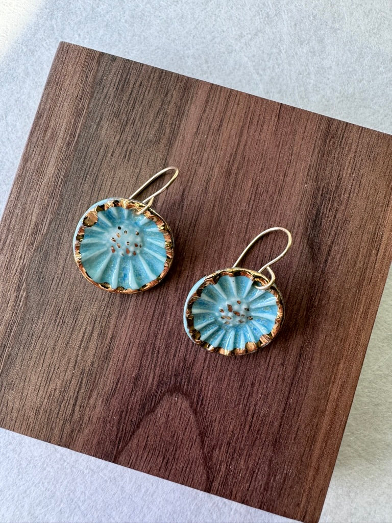 Handcrafted porcelain Anemone earrings with a blue glaze, sculptural radial texture, and hand-applied 22k gold accents.