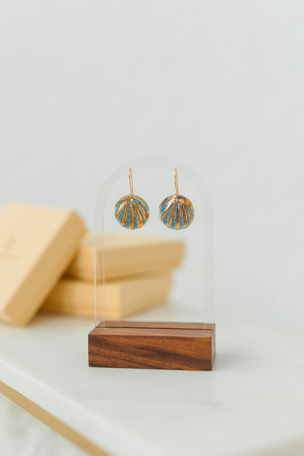 Blue handcrafted porcelain Maris earrings featuring shell-inspired relief and hand-applied 22k gold details.