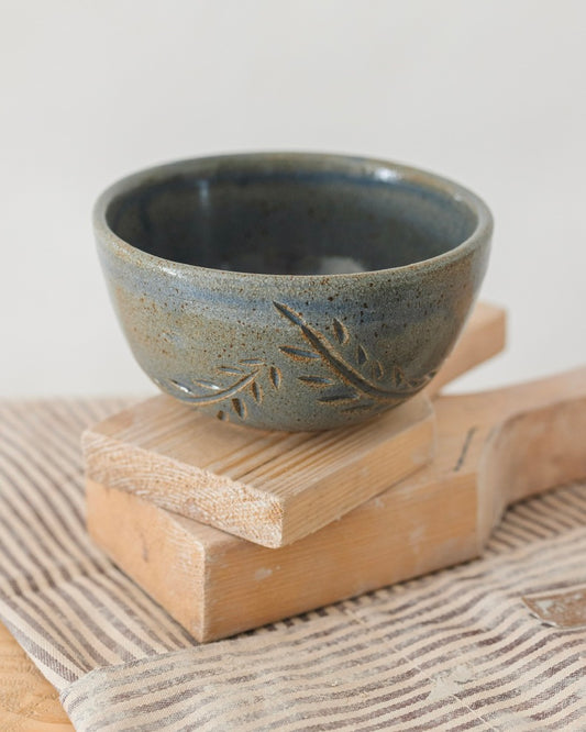 Ceramic bowl with leaf design on a wooden block