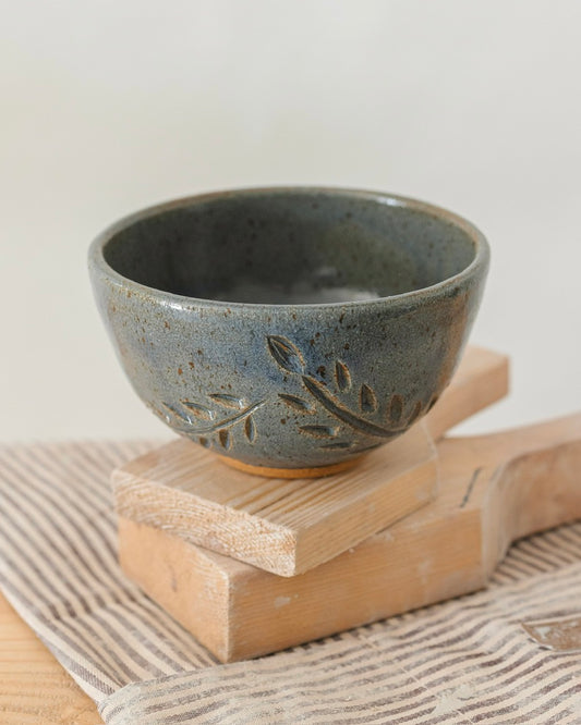 Blue ceramic bowl with leaf patterns on a wooden block