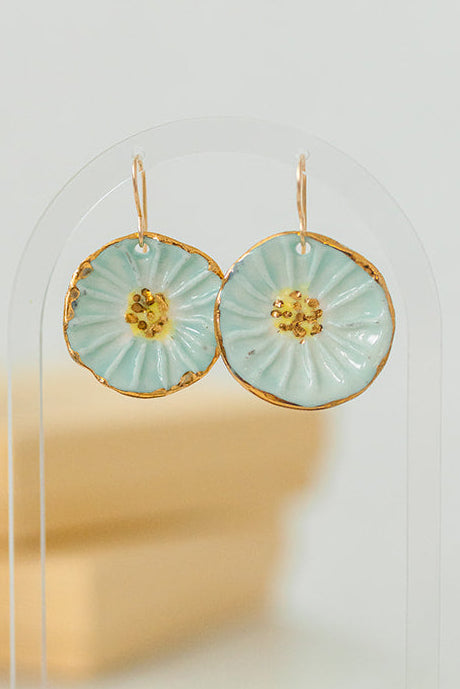 Round handcrafted porcelain flower earrings featuring a soft turquoise glaze and 22k gold details.