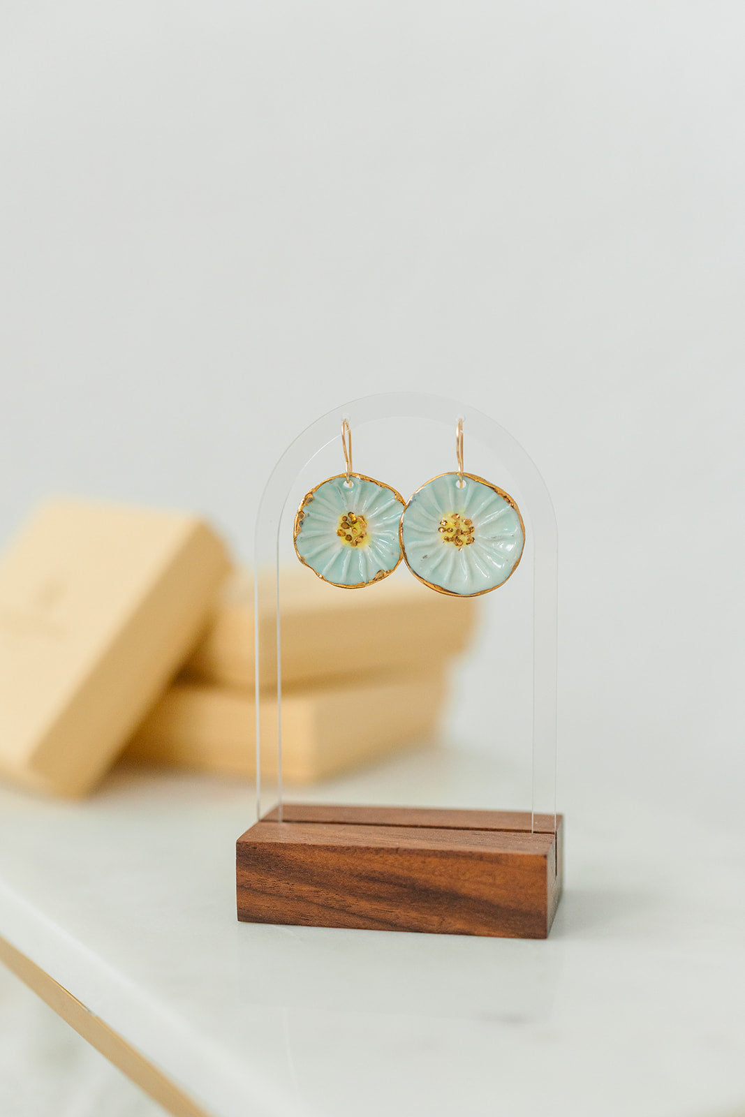 Round handcrafted porcelain flower earrings featuring a soft turquoise glaze and 22k gold details.