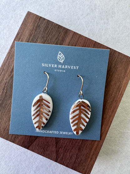 White porcelain leaf earrings featuring hand-applied 22k gold botanical details and gold-filled ear wires.