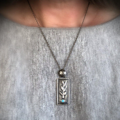 Handcrafted sterling silver necklace with a botanical branch design and Sleeping Beauty turquoise stone.