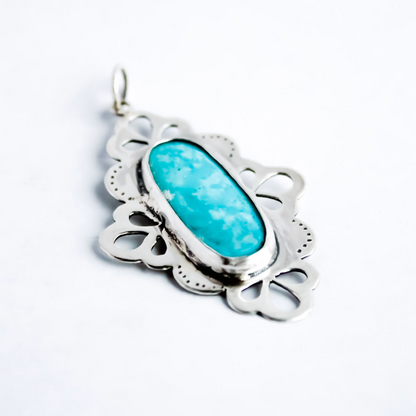 Handcrafted sterling silver pendant with a natural turquoise stone and lace-inspired openwork details.