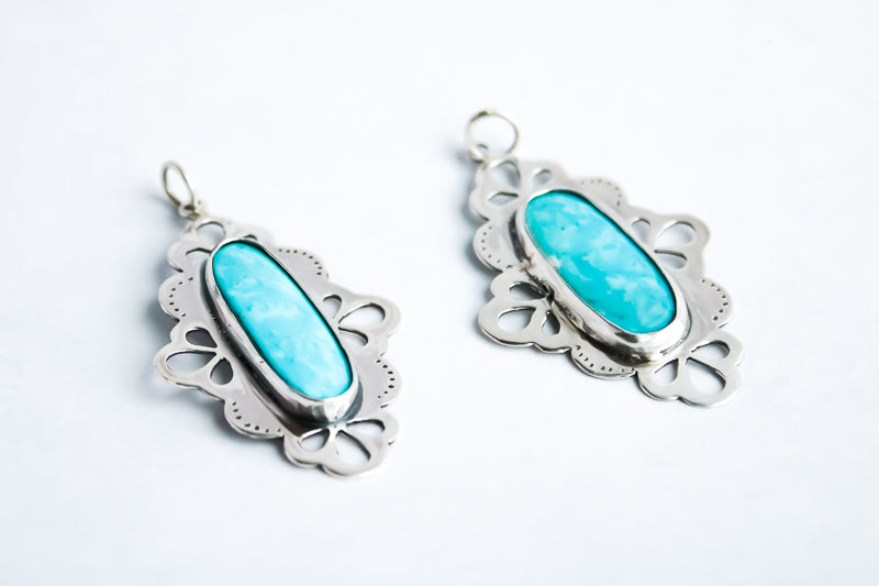 Handcrafted sterling silver pendant with a natural turquoise stone and lace-inspired openwork details.